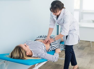Foto von Ärztin beim Abtasten der Bauchregion einer Patientin