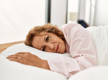 Foto von einer erschöpften Frau, die im Bett liegt 