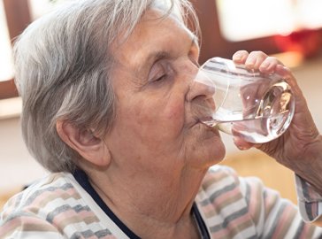 Foto einer Seniorin mit einem Glas Wasser
